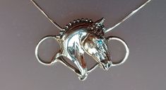 a silver necklace with a horse head on it's back end and blue eyes