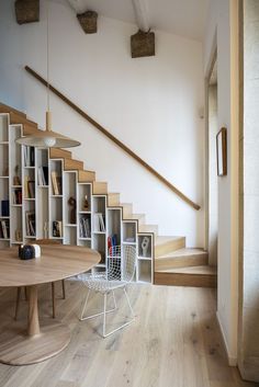 a wooden table sitting under a staircase next to a bookshelf