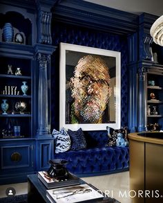 a living room filled with blue furniture and art work on the wall above it's coffee table