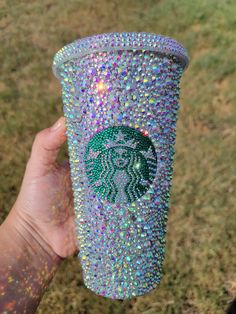 someone is holding up a starbucks cup covered in jewels and sparkles on the outside