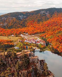 an aerial view of a town surrounded by mountains and trees with fall foliage in the foreground