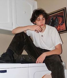 a young man sitting on top of a dryer