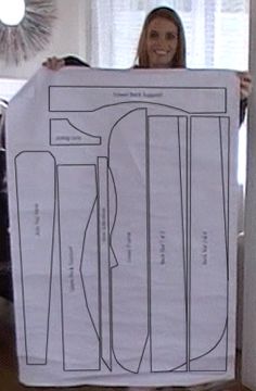 a woman holding up a paper cut out of her sewing pattern, with the instructions for it