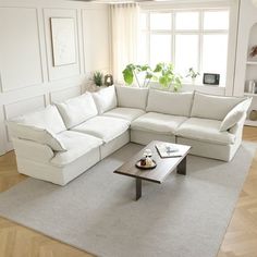 a living room with white furniture and wood floors