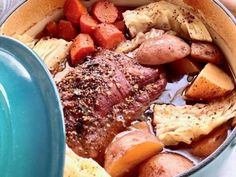 a pot filled with meat and vegetables on top of a table next to a person