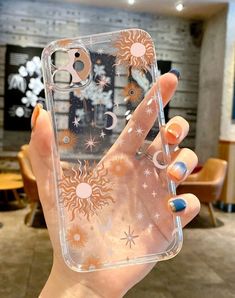 a woman holding up her phone case with sun and moon designs