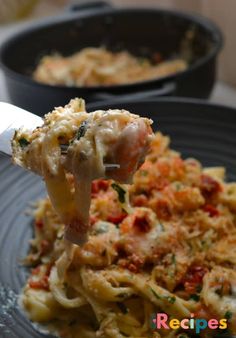 a fork full of pasta with meat and cheese on it is being lifted from a black plate