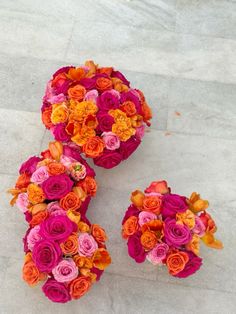 two vases filled with colorful flowers sitting on top of a cement floor next to each other