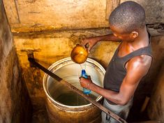 a man is pouring water into a bucket with an apple on it and a wooden stick