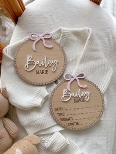 two wooden badges that say baby's name and date on them, sitting next to a teddy bear