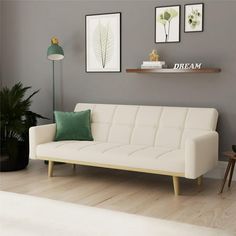 a white couch sitting in a living room next to a green pillow on top of a wooden table