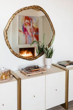 a mirror that is on top of a dresser next to a potted plant and a record player