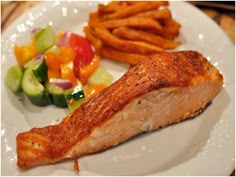 a white plate topped with salmon and french fries