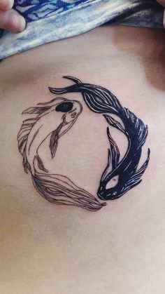 a woman's stomach with a tattoo design on the side of her belly and an image of two fish in a circle