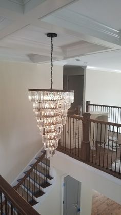 a chandelier hanging from the ceiling in a room with stairs and railings