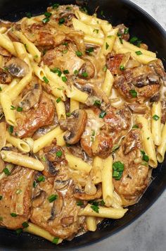 a skillet filled with pasta and meat covered in mushroom sauce, garnished with parsley