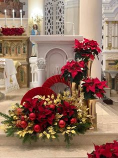 a church decorated for christmas with poinsettis and other holiday decorations in front of the alter