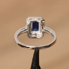 It is real created sapphire ring, the emerald cut sapphire is about 5mm*7mm. The basic metal is sterling silver and plated with rhodium. To change the metal to a solid gold (white/rose) or platinum is also available, please ask for a quotation if you want. You can also go to my shop Home for more elegant rings: https://www.etsy.com/shop/godjewelry?ref=hdr_shop_menu Sapphire is the birthstone of September. More sapphire rings: https://www.etsy.com/shop/godjewelry?ref=listing-shop2-all-items-count Sapphire Emerald-cut Halo Jewelry, Emerald Cut Sapphire Jewelry With Halo Setting, Emerald-cut Sapphire Birthstone Ring, Emerald Cut Sapphire Diamond Ring For Promise, Emerald Cut Lab-created Sapphire Promise Ring, Lab-created Sapphire Baguette Cut Promise Ring, Rectangular Lab-created Sapphire Ring For Anniversary, Anniversary Rectangular Lab-created Sapphire Ring, Fine Jewelry Emerald Cut Diamond Ring With Lab-created Sapphire