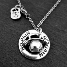 two necklaces with words on them sitting on top of a black surface, one has a chain and the other has a silver ball