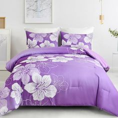 a bed with purple and white flowers on the comforter is shown in this room