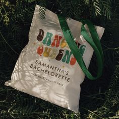 a tote bag sitting in the grass with a green ribbon around it's neck