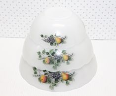 three white dishes with fruit on them sitting on top of each other in front of a polka dot wall