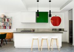 three stools sit in front of an island with two apples on the back wall