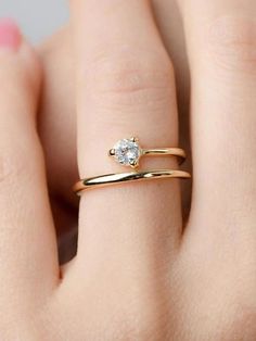 a woman's hand wearing a gold ring with a white diamond on the side