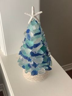 a blue and white christmas tree made out of sea glass with a starfish on top