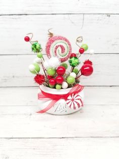 a candy cane arrangement in a small white bowl with red and green candies on top