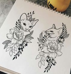 an open notebook with two drawings of cats and flowers on the pages next to it