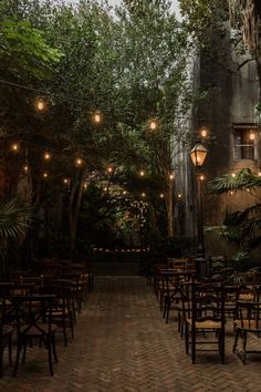 tables and chairs are lined up in the middle of an outdoor patio with hanging lights