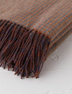 an orange and brown plaid blanket laying on top of a white surface with water droplets