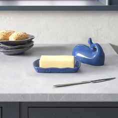 a counter with some food on it and a blue bowl filled with cheese next to bread