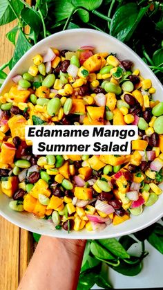 someone holding a bowl full of food with the words edamame mango summer salad