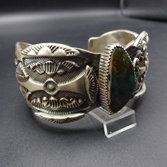 "VINTAGE MARC ANTIA BRACELET DESCRIPTION: This outstanding cuff is from celebrated Apache artisan, Marc Antia. Deep and intricate hand-stamped designs enhance the heavy gauge sterling silver cuff. The dark blue-green Pilot Mountain cab sits up high in picket fence bezel. This museum quality bracelet will be a cherished addition to your collection of fine vintage Native American jewelry. MEASUREMENTS: Interior of the cuff measures 6\" with an additional 1 1/8\" non-adjustable gap. Total circumfer Vintage Ceremonial Stamped Cuff Bracelet, Vintage Etched Cuff Bracelet, Vintage Engraved Cuff Bracelet For Ceremonial Occasions, Vintage Collectible Cuff Bangle Bracelet, Vintage Collectible Bangle Cuff Bracelet, Vintage Stamped Jewelry For Ceremonial Occasions, Vintage Ceremonial Stamped Jewelry, Vintage Patina Cuff Bracelet, Vintage Stamped Cuff Bracelet Bangle