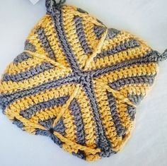 a yellow and gray crocheted dishcloth laying on top of a white surface