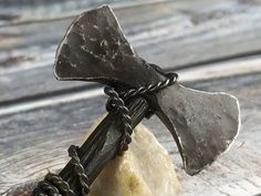 an old hammer and some kind of rock on a wooden table with chains around it