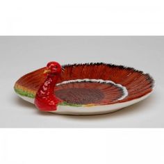 a small red and green bowl with a turkey on the bottom, sitting in front of a white background