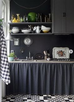 a kitchen with black and white checkered flooring next to a counter topped with dishes