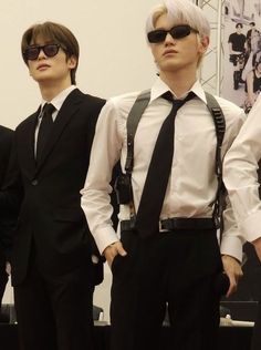 three men in suits and sunglasses standing next to each other with their hands on their hipss