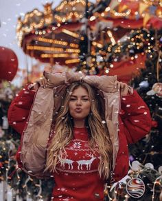 a woman standing in front of a christmas tree wearing a red sweater with reindeers on it