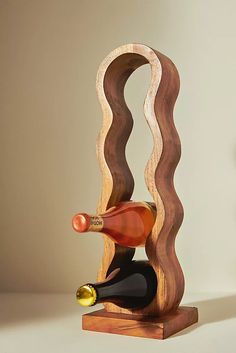 a wine bottle holder made out of wood with a wavy design on the top and bottom