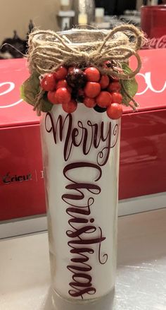 a can with some berries on top of it and the words merry christmas written in brown lettering