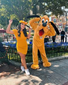 a woman in a winnie the pooh costume poses next to pluto the dog mascot