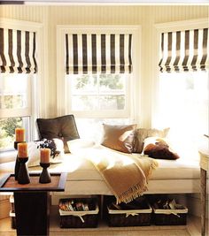 a living room filled with lots of furniture and windows covered in striped roman blind shades