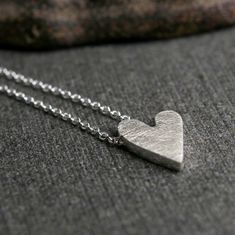 "Sterling silver handmade tiny dainty heart charm pendant necklace This is a truly tiny heart. A truly tiny heart doesn't mean you love any less...it just means you don't need to shout from the rooftops. It's a subtle sign that you are loved. Cut from a solid chunk of sterling silver it measures about 1/2\" long (1.25cm) and 1/4\" wide. This pendant is perfect for every day. A brushed finish adorns the front and my logo and sterling stamp grace the back. The chain travels through the pendant for Minimalist Handmade Heart Necklace For Everyday, Everyday Minimalist Handmade Heart Necklace, Simple Silver Heart Pendant Necklace, Handmade Sterling Silver Heart Charm Necklace, Nickel-free Minimalist Sterling Silver Heart Necklace, Handmade Heart-shaped Sterling Silver Charm Necklace, Simple Silver Heart Charm Necklaces, Simple Silver Heart Charm Necklace, Simple Sterling Silver Heart Charm Necklace