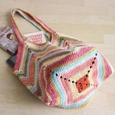 a crocheted bag sitting on top of a wooden floor next to a magazine