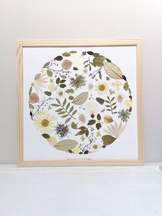 a white framed artwork with flowers and leaves on it