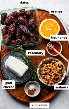 an assortment of different foods on a wooden platter with oranges, yogurt, nuts and honey